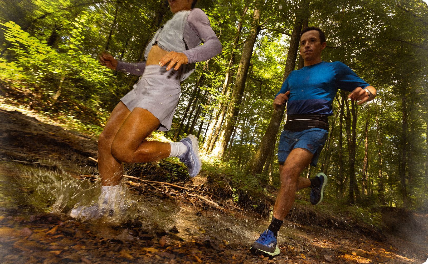 People running on a trail through the woods.
