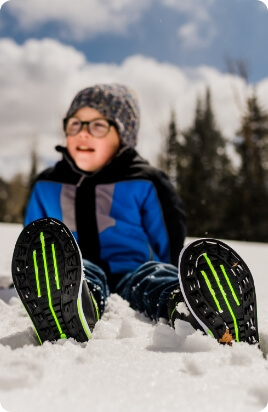 Child in snow wearing boots.
