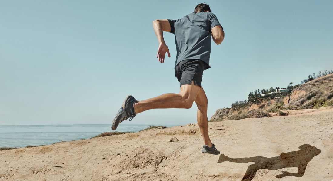 Person running on the beach wearing Merrell Trail Glove shoes.