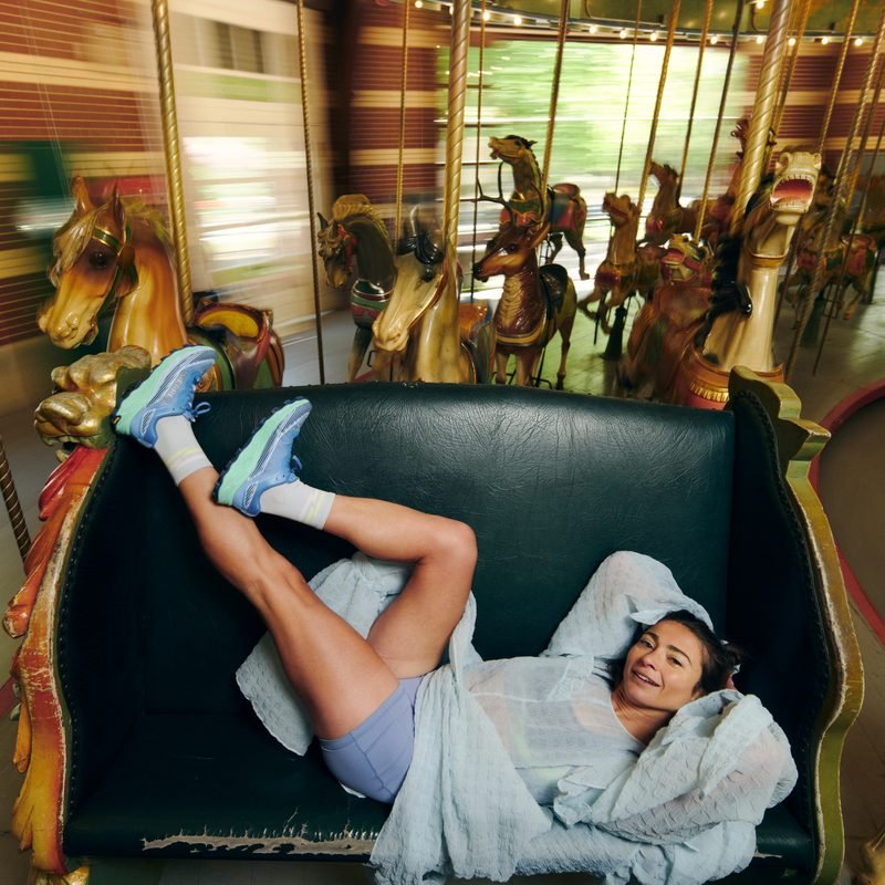 Alexi Pappas reclining on a carousel bench mid-ride
