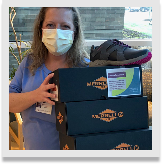 Nurse holding boxes of Merrell footwear.