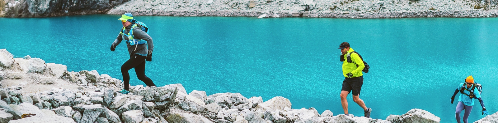 3 people running on a scree slope by a lake