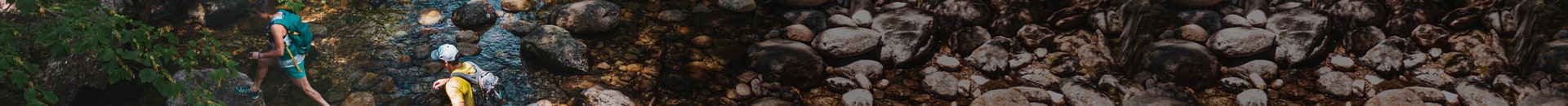 Two people out for a hike, crossing a creek.