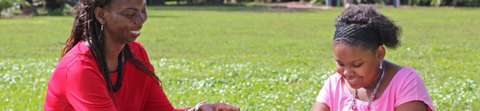 Adult and child sit in a field.