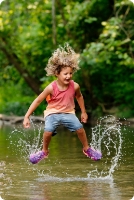 Happy Kid with hair flying jumping and splashing in a stream.
