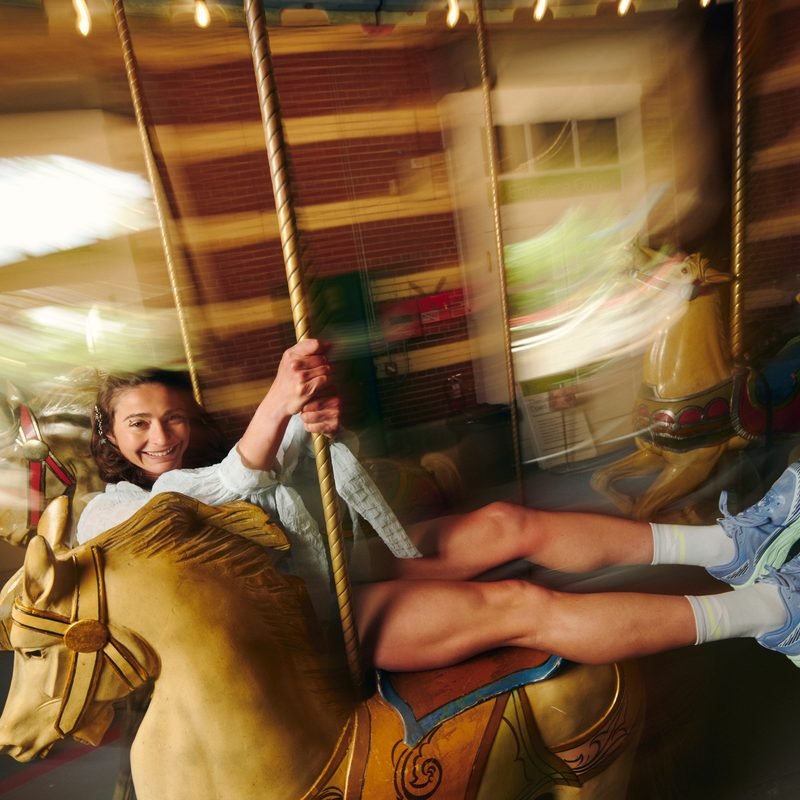 Alexi Pappas laughing on a spinning carousel horse
