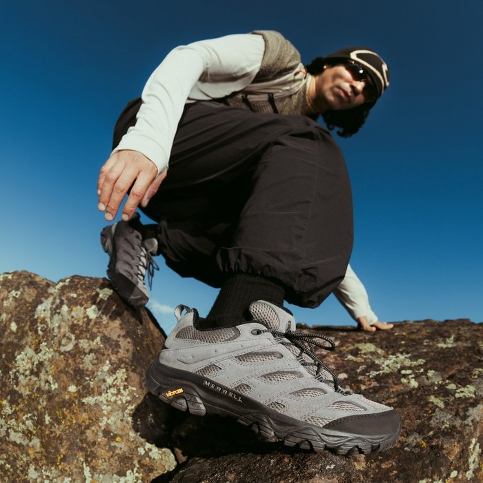 Man crouching on a rock wearing Merrell Moab 3 hiking shoes