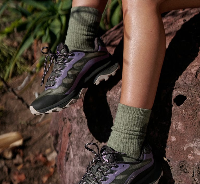 Legs sitting on a rock wearing Repreve socks.