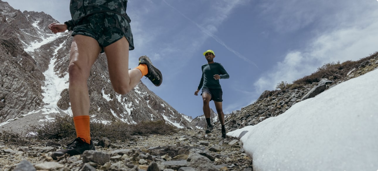 People running through the mountains wearing new Merrell gear.