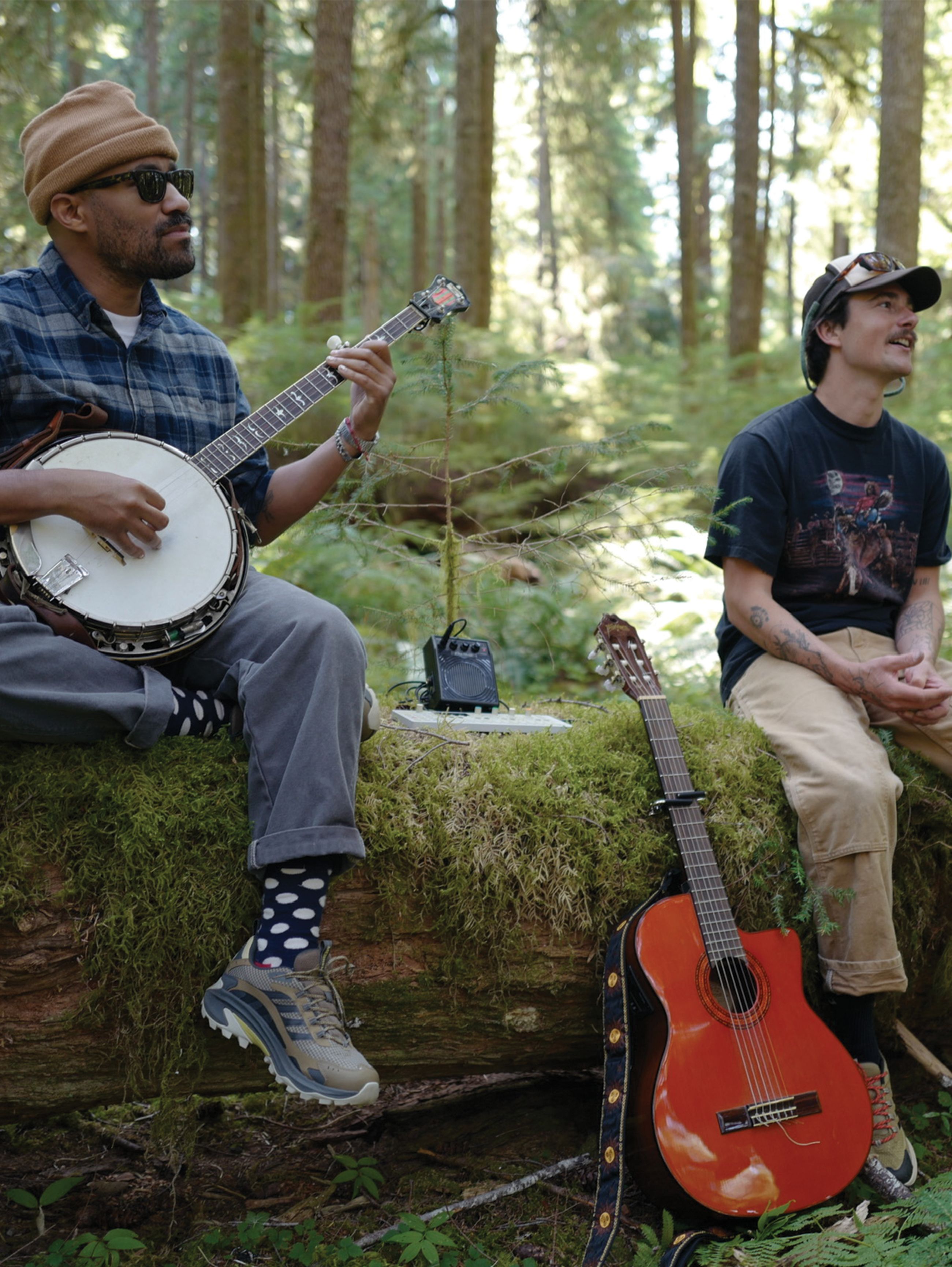 Person looking cool wearing a Outside hat, sunglasses, and a Merrell shirt holding a Merrell shoe next to their face.