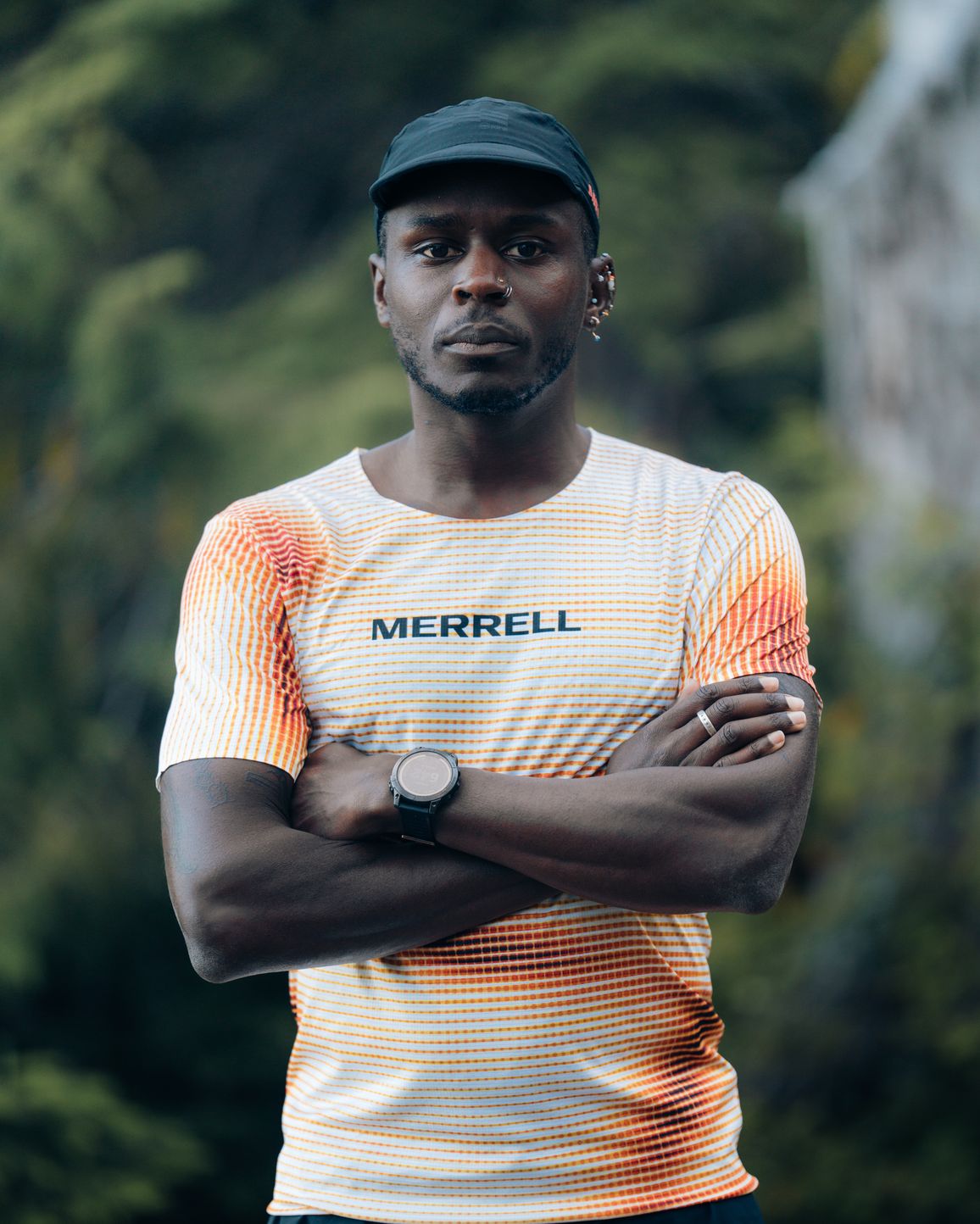 Merrell athlete Coree Woltering standing with his arms crossed on a wooded trail.