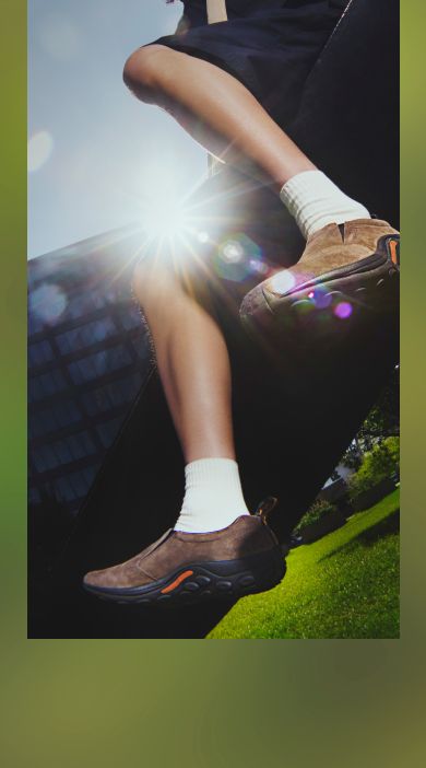 Person sitting on a rock at the beach wearing Merrell sandals