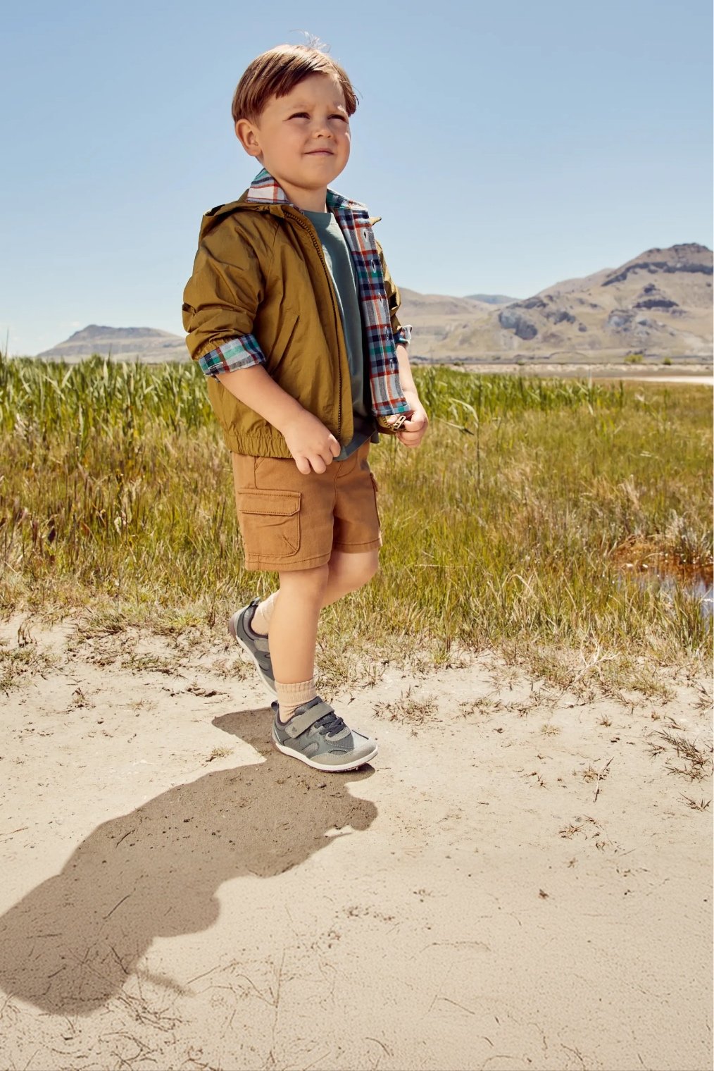 Little kid walking through a field wearing Merrell shoes