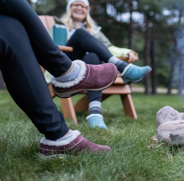 People sitting by an outdoor fire, wearing Merrell mocs.