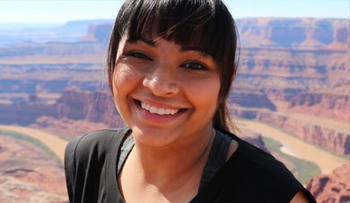 Ambreen Tariq smiling while standing atop of the canyon walls of the west.