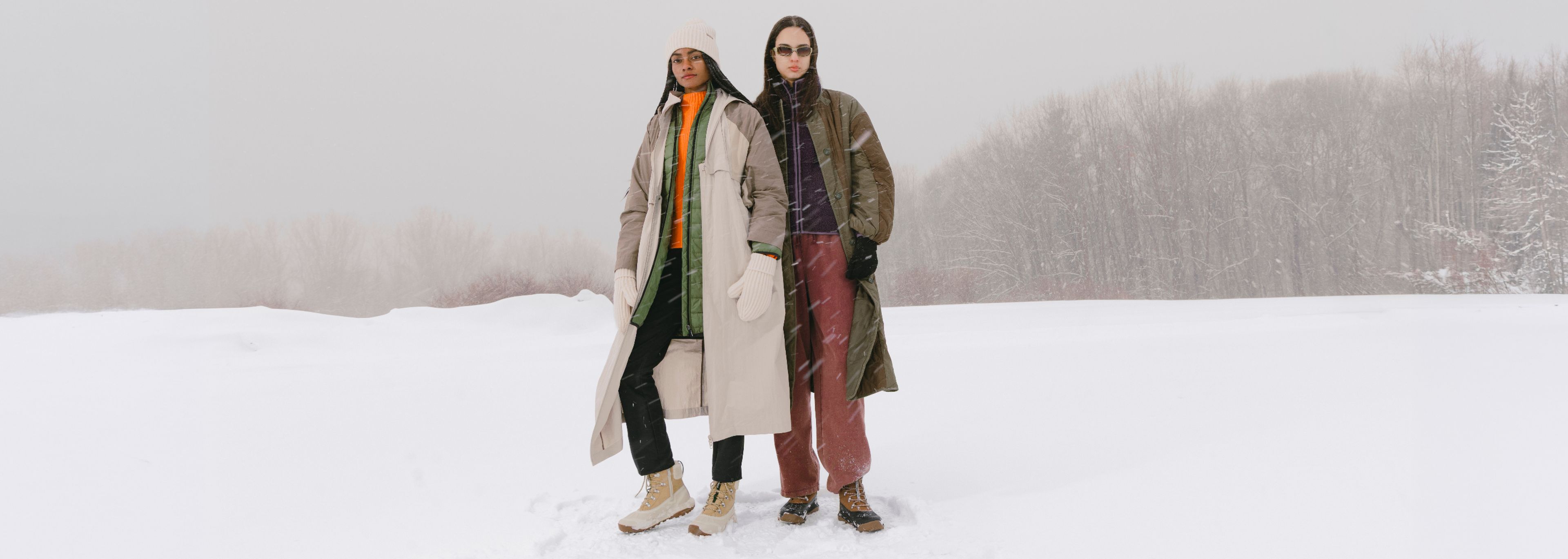 Two people wearing Merrell winter boots in a snowy landscape.