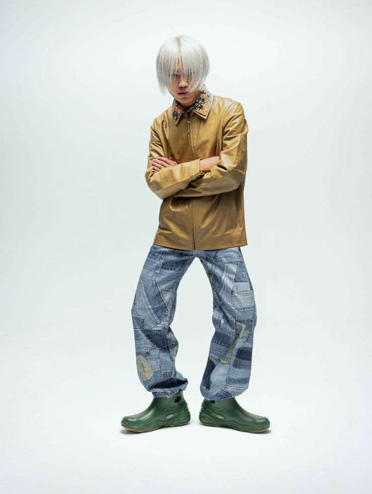 a man with white hair and a yellow jacket with his arms crossed