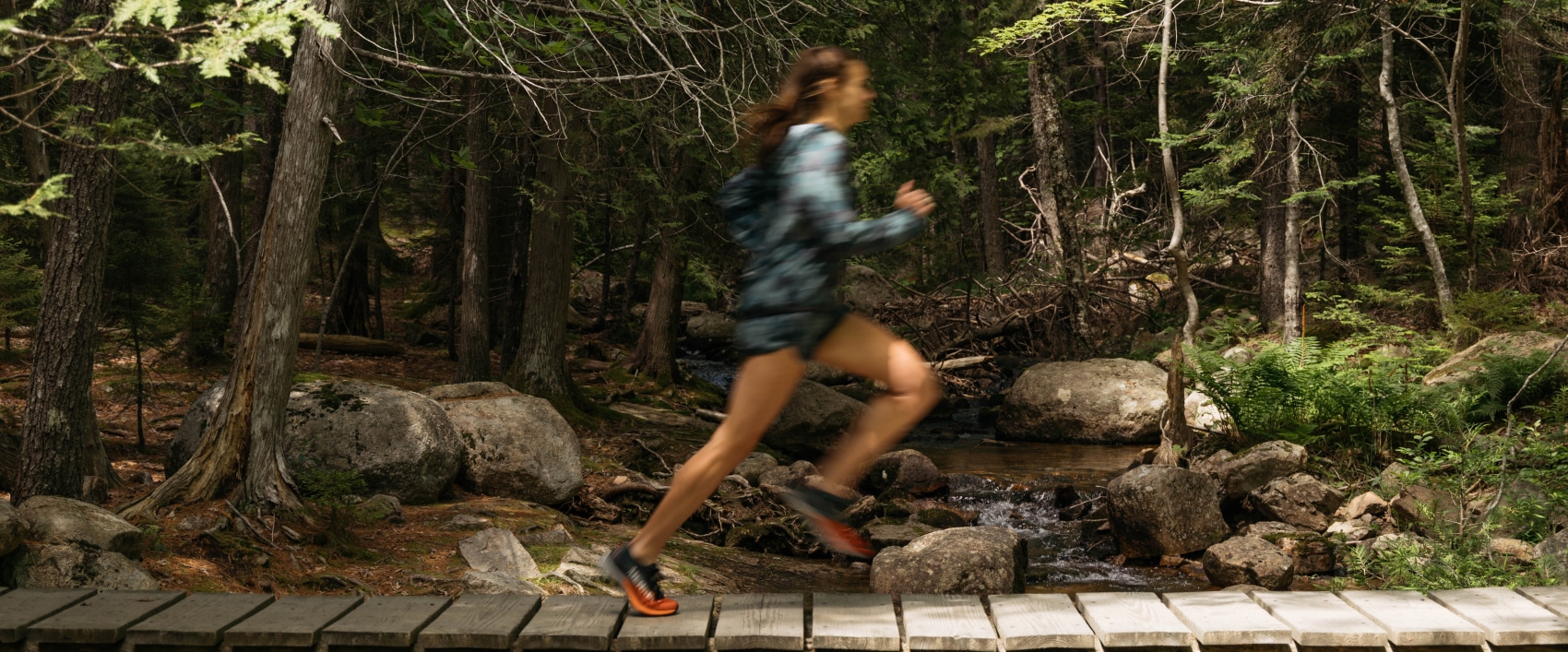 Rachel Tomajczyk running through the woods wearing Merrell gear, looking fast.