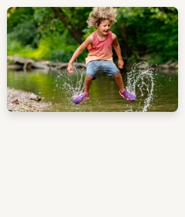 Happy Kid with hair flying jumping and splashing in a stream.
