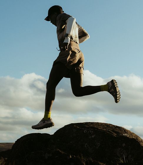 Person running outside in Merrell trail running shoes.