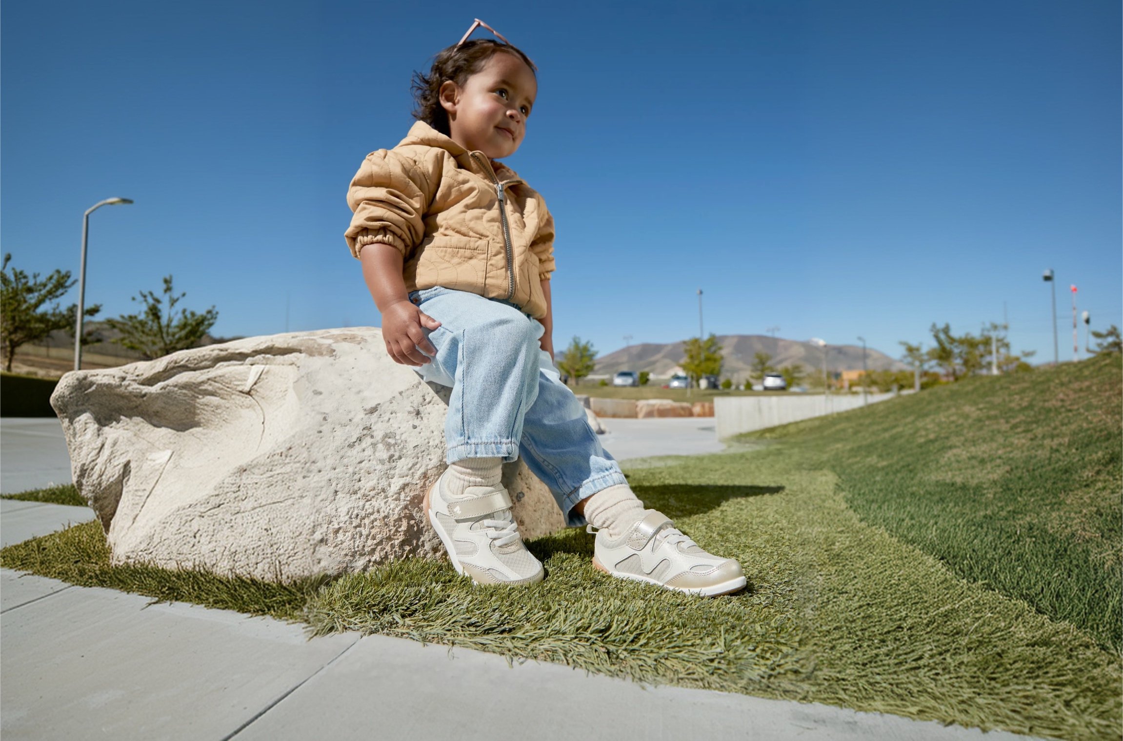 Two kids holding hands on a rock wearing Merrell shoes