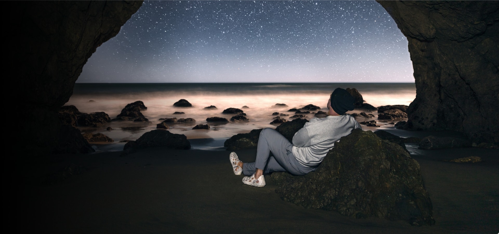Person laying out under the stars in a cove, looking relaxed wearing Merrell gear.