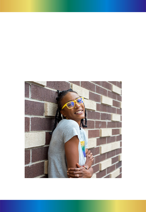 Latasha smiling while leaning against a brick wall.