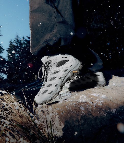 Light grey Merrell hiking boots on a snow-covered rock.