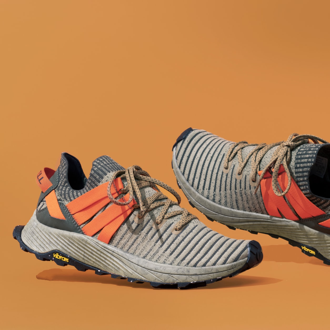 A pair embark lace sneakers sitting on the floor with a colored background.