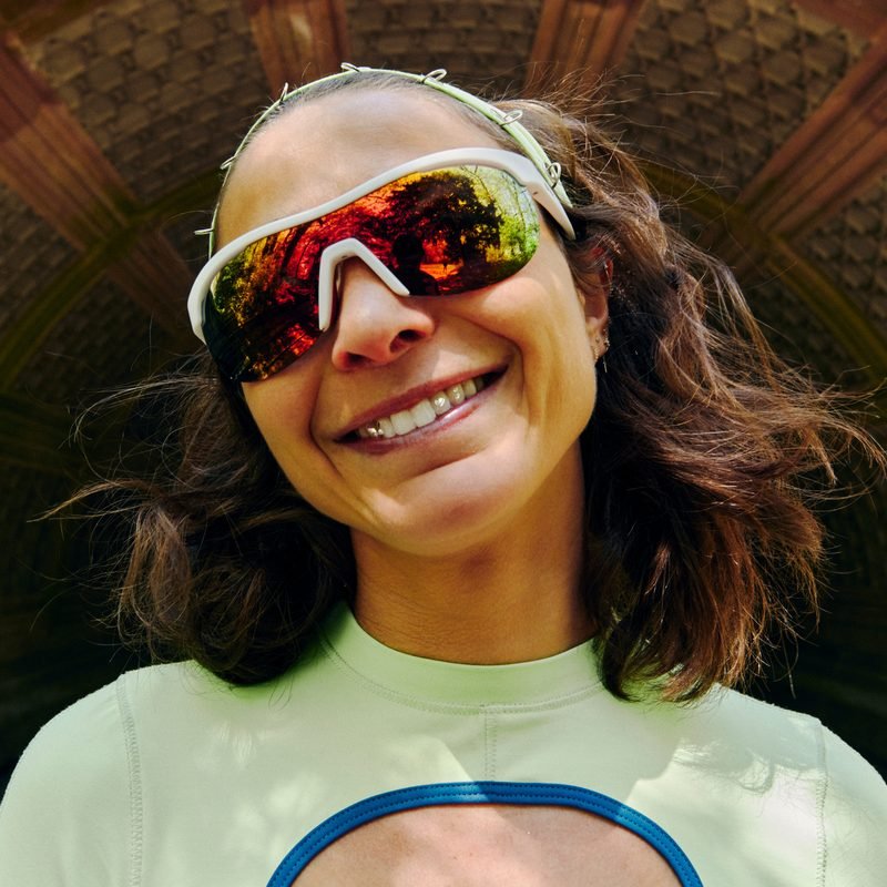 Alexi Pappas smiling in sunglasses beneath a tiled archway