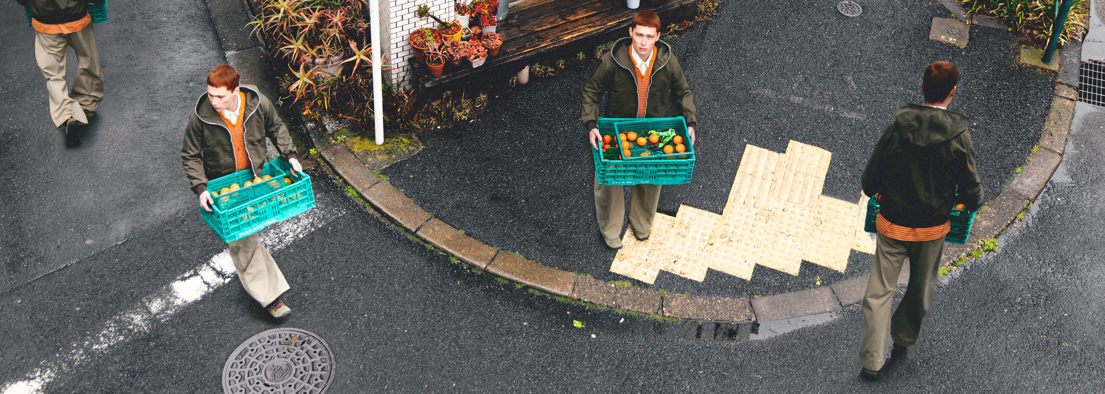A person wearing Merrell shoes carrying a basket of fresh fruit.