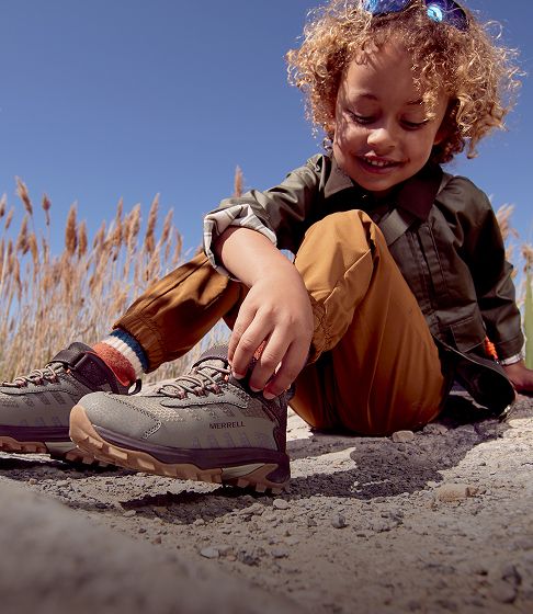 Child putting on shoes outdoors.