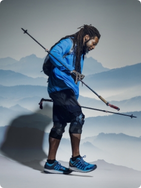 Person wearing blue Merrell gear holding trekking poles.