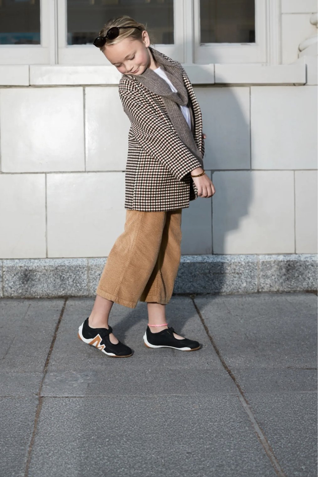 Big kid posing against a wall wearing Merrell shoes