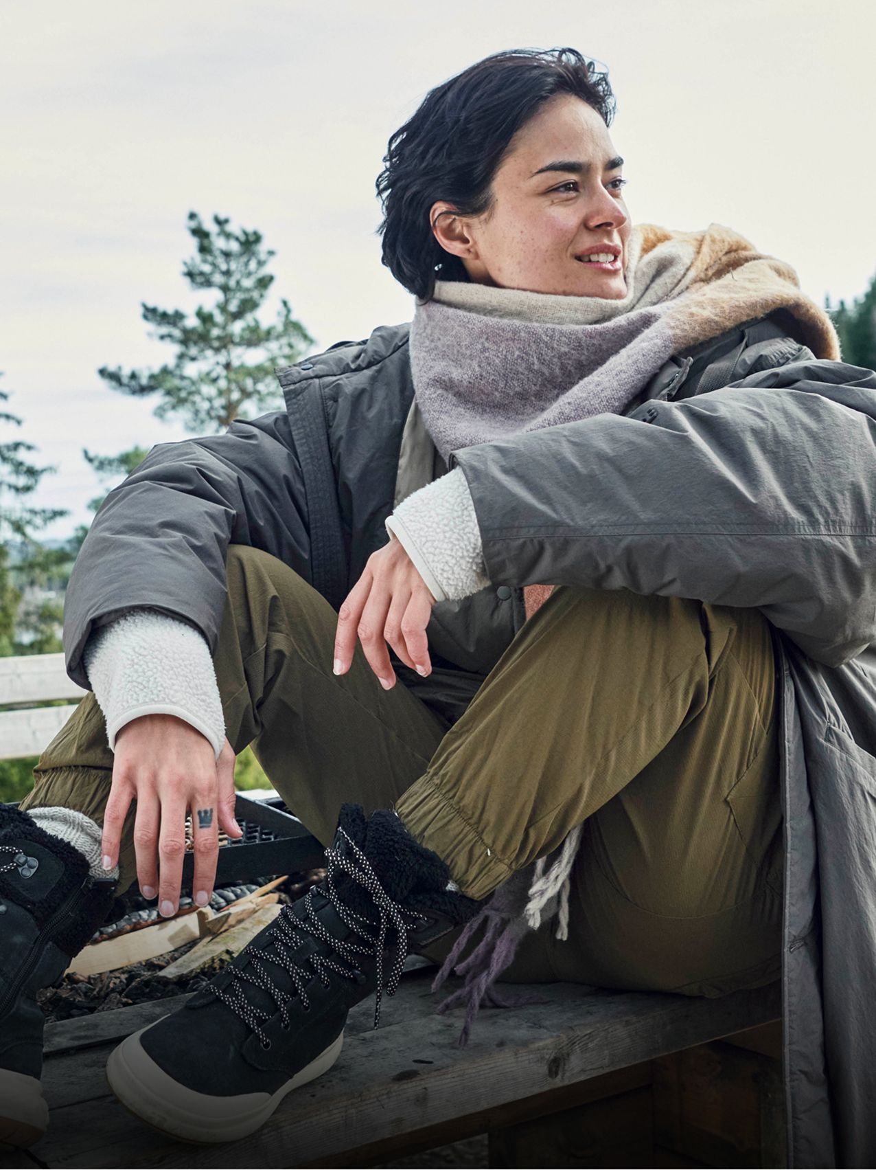 Young girl sitting on a rock, smiling, wearing colorful Merrell shoes.