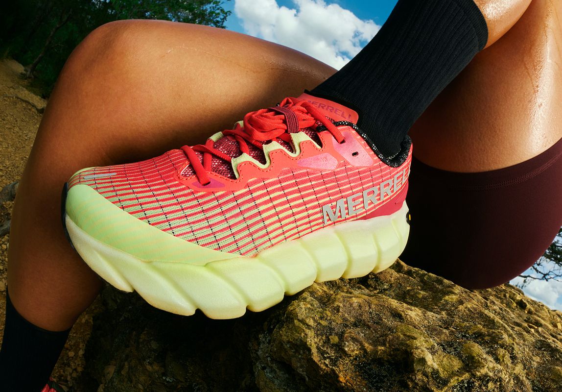 Persons legs sitting and wearing pink MTL Adapt Matryx shoe on a rock.
