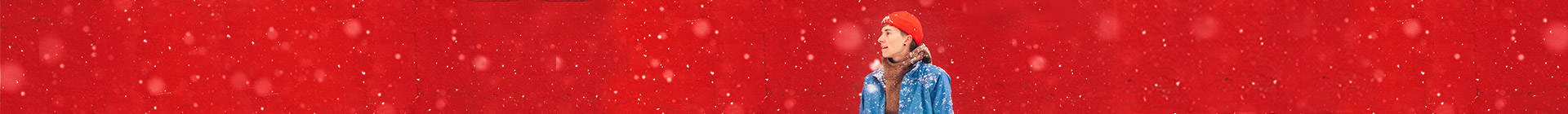 Teen boy standing in the snow with a red hat on and smiling