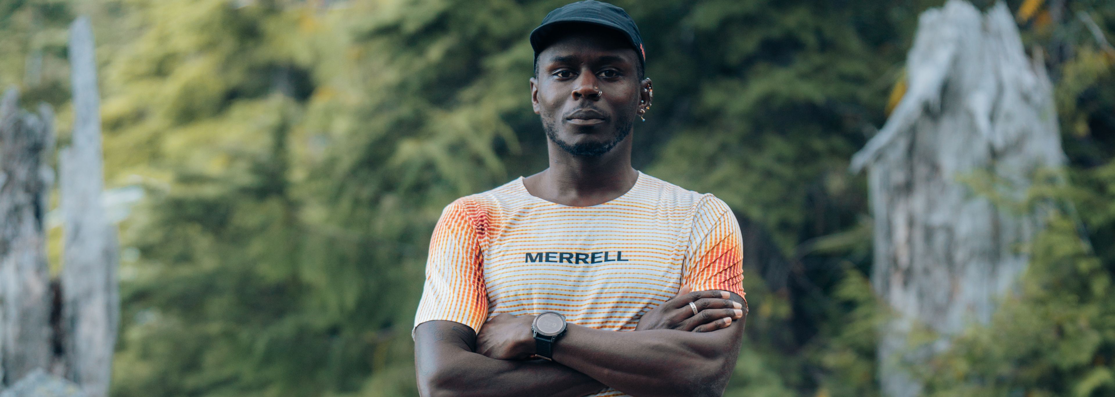 Merrell athlete Coree Woltering standing with his arms crossed on a wooded trail.