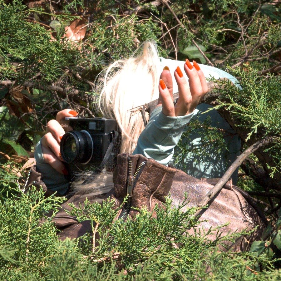 Portrait of photographer Luisa Opalesky lying in the grass with a camera