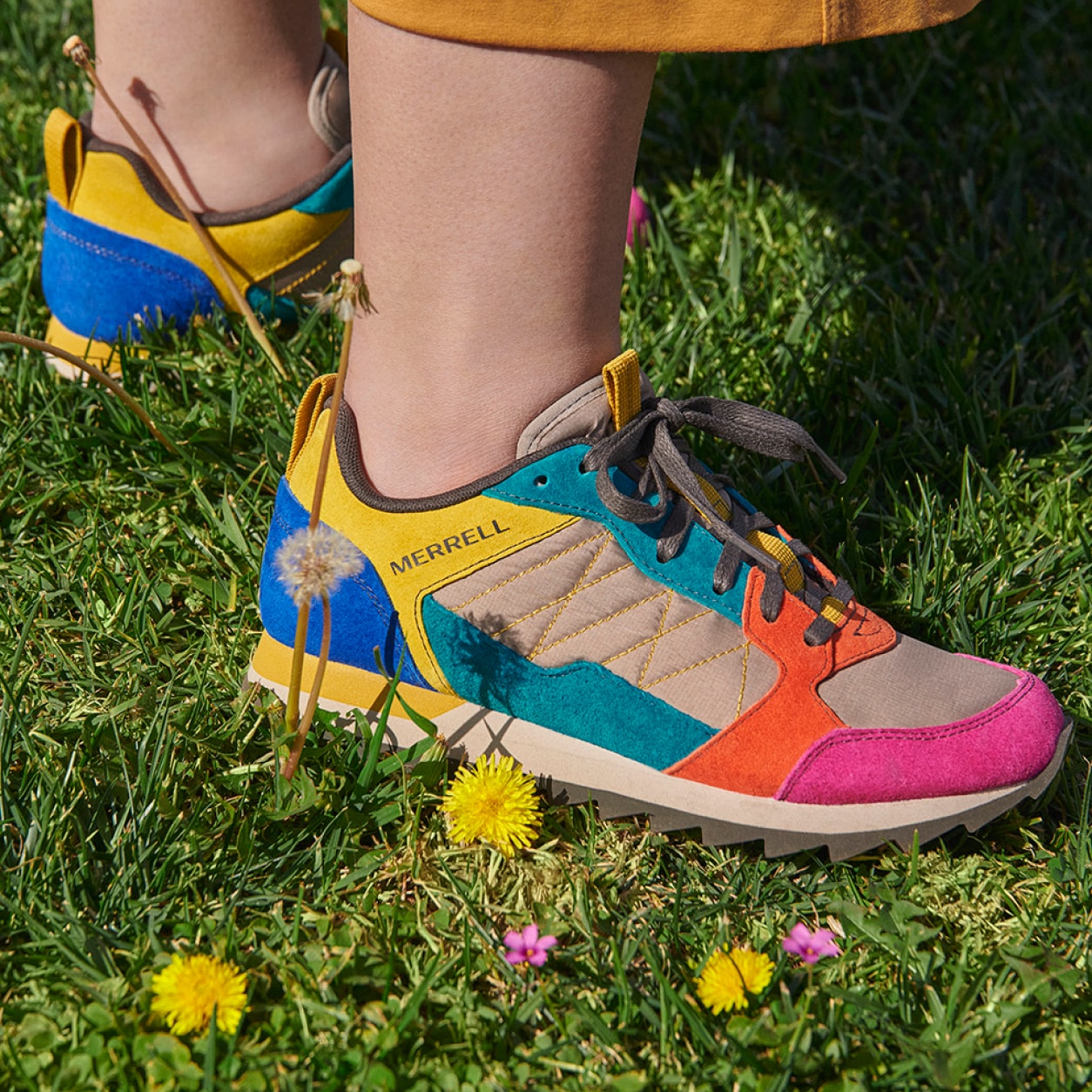 A person standing on the grass with a closeup shot of the alpine sneakers.