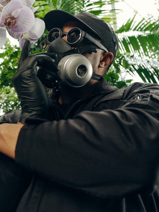 Mr. Flower Fantastic wearing a gas mask in front of tropical plants