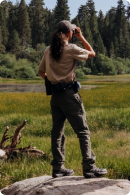 Two people standing on a rock looking out over a field wearing Merrel boots
