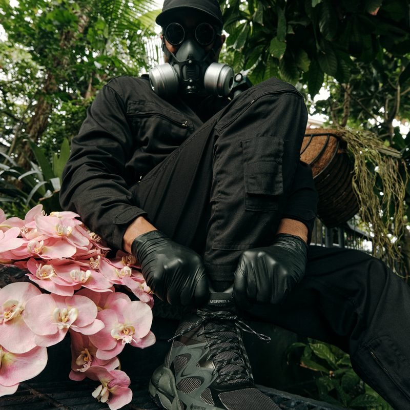 Mr. Flower Fantastic lacing a Merrell shoe beside pink orchids