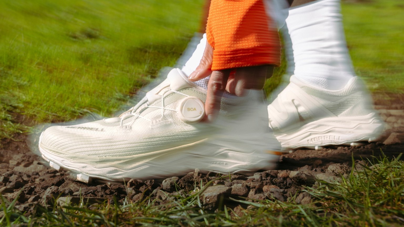 Close-up of a runner adjusting the BOA dial on a Merrell trail shoe