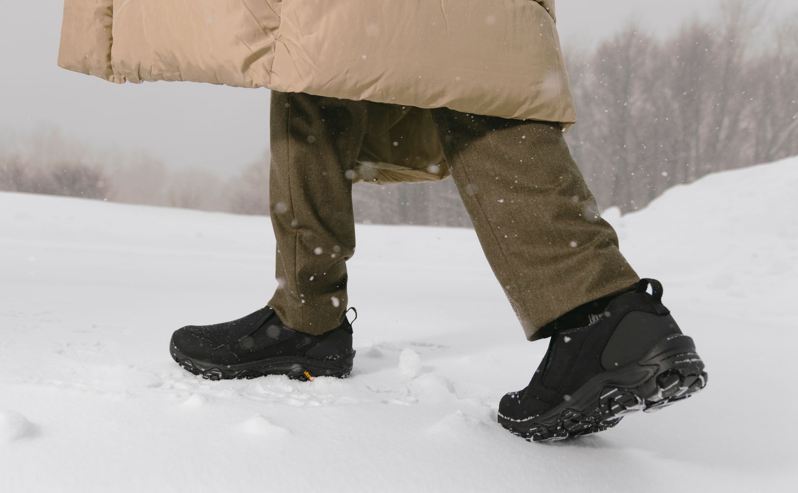 Black Merrell Coldpack winter boots worn on a snowy trail.
