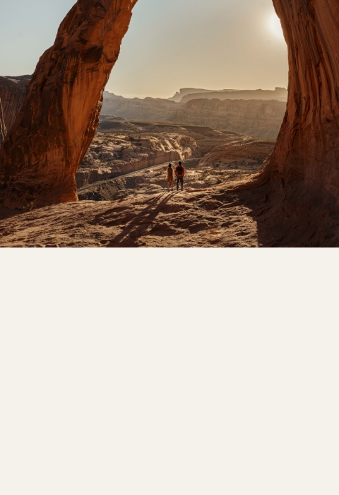Two people standing under an arch in the desert